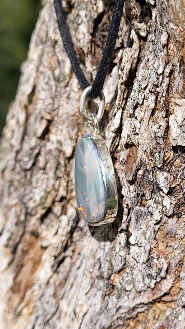 Pendentif Opale iridescente argent 925 Origine de la pierre:Coober Pedy Type de la pierre: Opale doublet sur shungite Forme: Cabochon de forme libre, arronidie Taille:3cm/1,9cm/0,4cm Poids:4,9g Prix: 160€