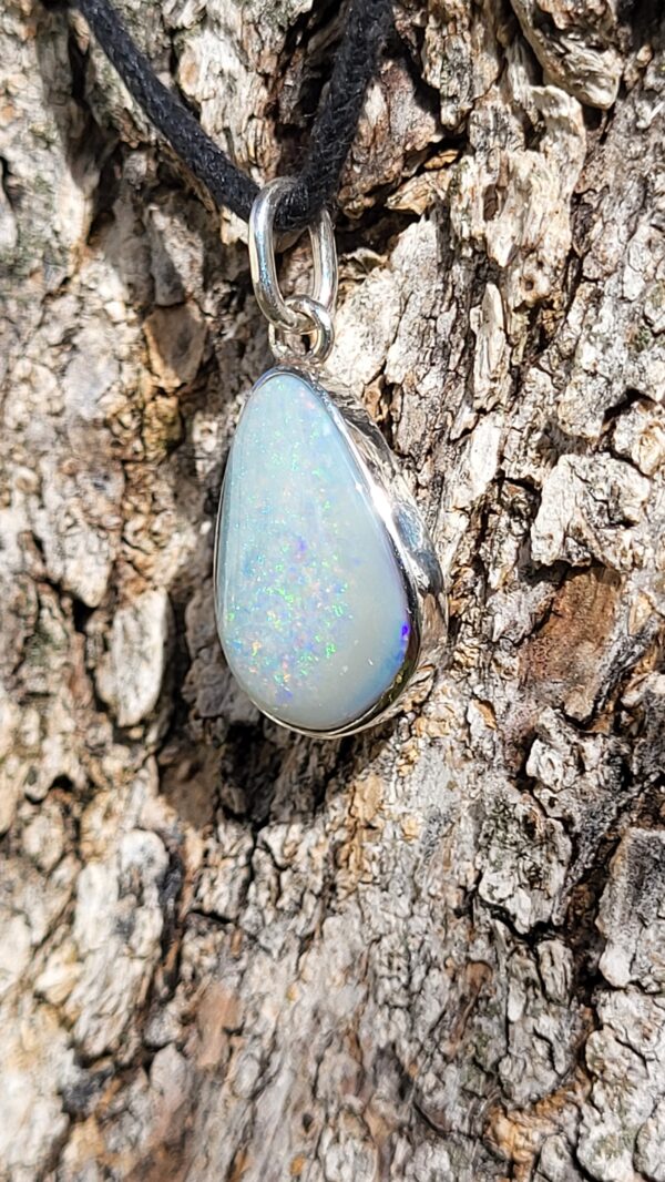 Pendentif en Opale Australienne, sur argent 925. Opale blanche aux iridescences arc-en-ciel multicouleur. De forme type poire ou goutte, avec une bélière en breloque.