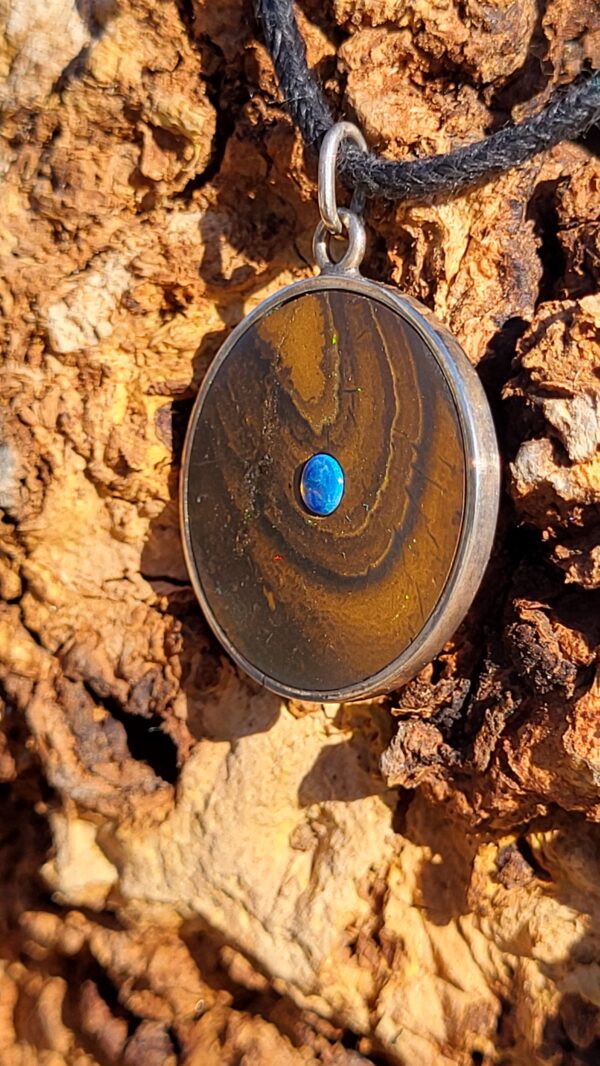 Pendentif rond en opale boulder d'Australie, avec une opale cristal bleu en son centre. Le bijou est en argent 925.