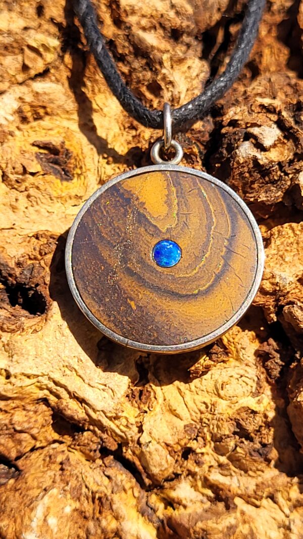 Pendentif rond en opale boulder d'Australie, avec une opale cristal bleu en son centre. Le bijou est en argent 925.